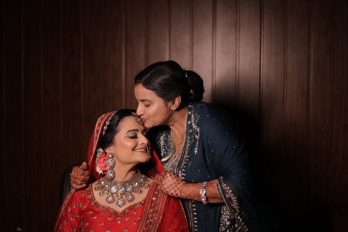 Emotional moment of mother kissing bride on the forehead at Indian wedding