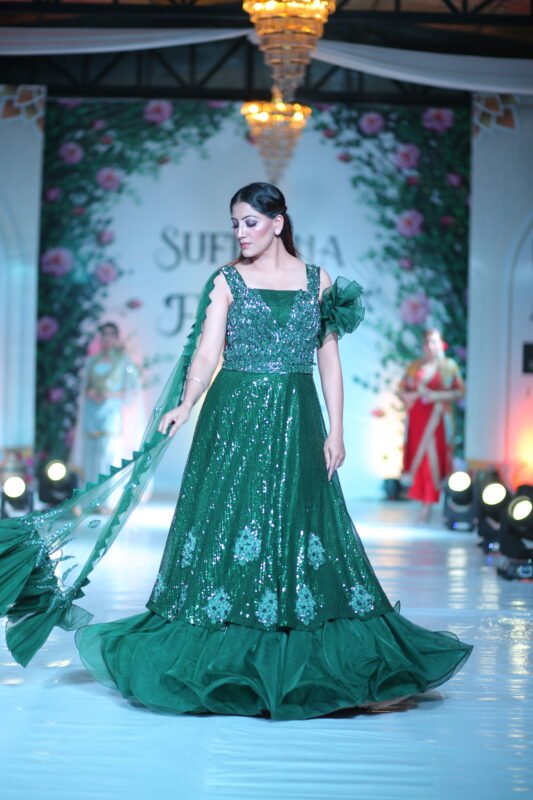 Female model walking the runway in a deep green traditional designer lehenga