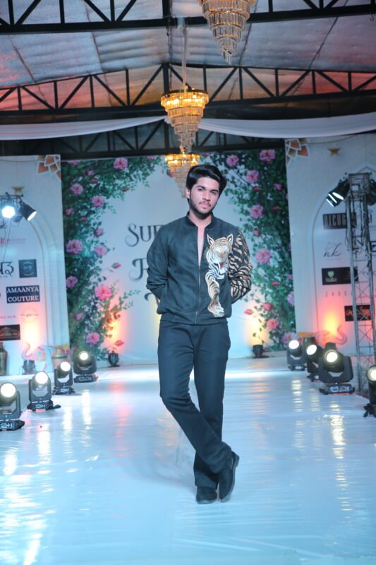 Male model presenting modern black designer outfit on fashion show ramp