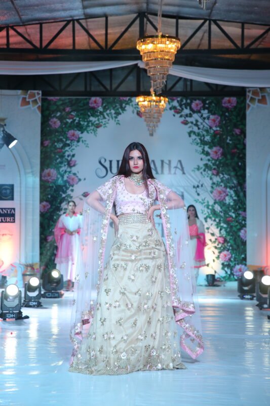 Female model presenting traditional cream and pink lehenga on the ramp