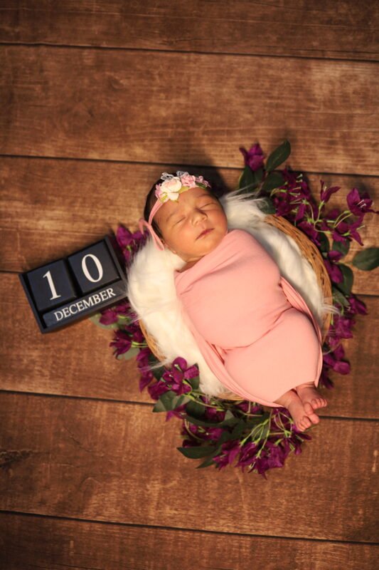 Newborn baby milestone photography with floral arrangement