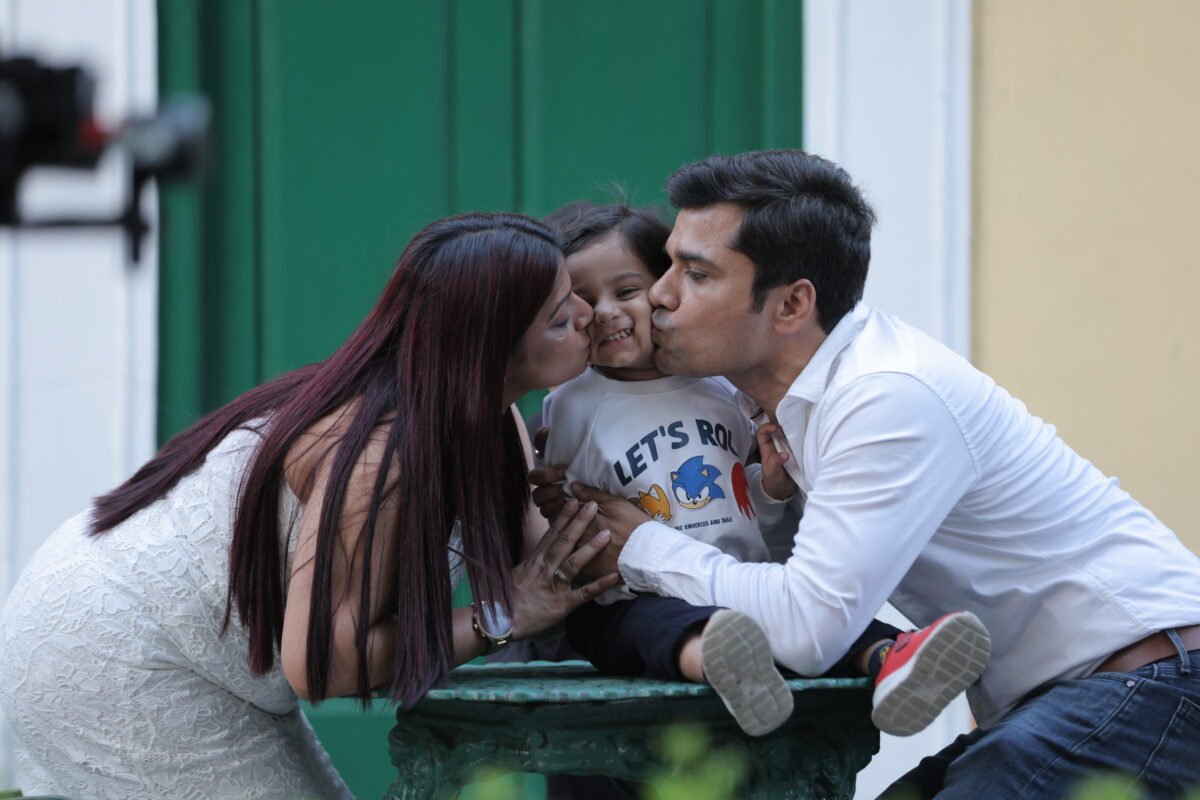 Parents kissing their child during a family photoshoot
