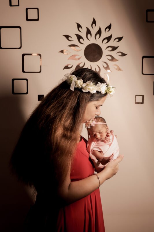Mother holding newborn baby girl during photoshoot