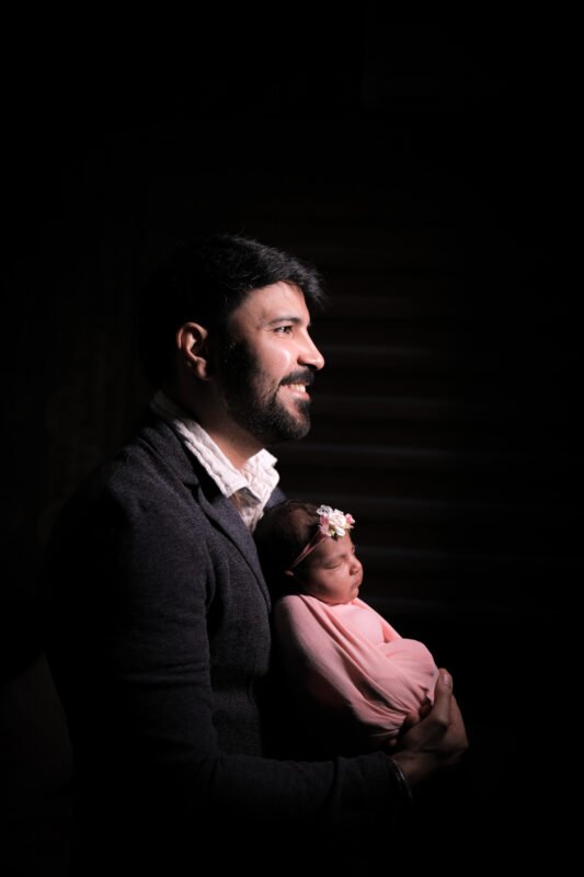 Dad holding newborn baby during photoshoot in Noida