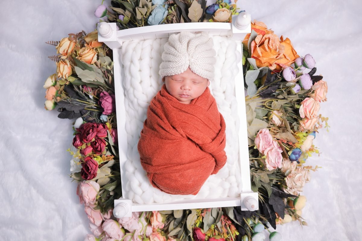 Newborn baby sleeping in basket with flowers