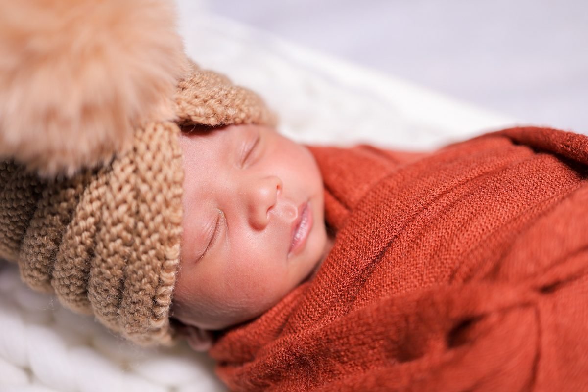Sleeping newborn baby in orange wrap